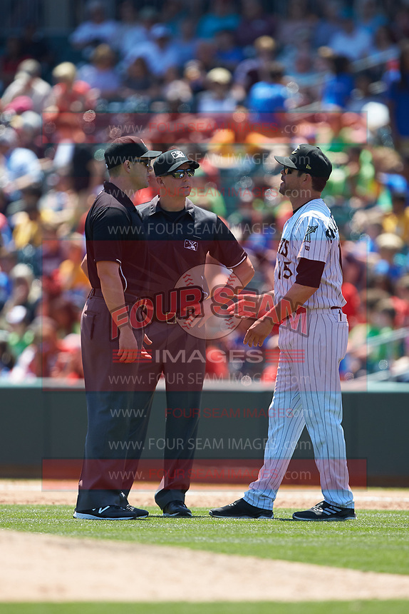 Charlotte Knights manager Mark Grudzielanek (15) discusses a call with first base umpire Shane Livensparger (center) and second base umpire Adam Beck during the game against the Gwinnett Stripers at BB&T BallPark on May 2, 2018 in Charlotte, North Carolina. The Knights defeated the Stripers 6-5. (Brian Westerholt/Four Seam Images)