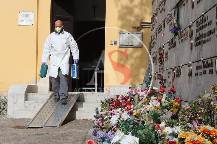 Europe Virus Outbreak - Cemetery Works in Pergine Valsugana, Italy on April 21, 2020. A sweeping lockdown is in place in Italy to try to slow down the spread of coronavirus pandemic. An employee wearing gloves and masks walks with small suite cases to treat a coffin.