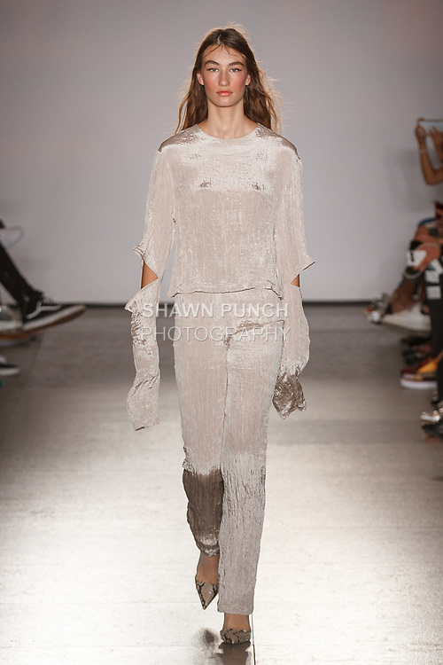 Model walks runway in a light tan delphos pleated long sleeve top and hand holes with light tan delphos pleated pants, from the Calvin Luo Spring Summer 2018 collection on September 12, 2017 at The Whitney Museum of American Art during NYFW: The Shows Spring Summer 2018.