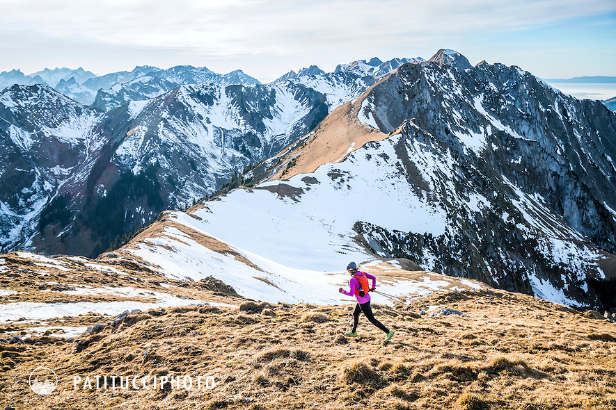 Trail running in a dry, brown landscape in the Gantrisch mountains of the pre-Alps, during a low snow winter in Switzerland.
