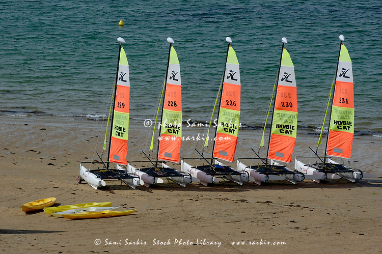 Five catamarans and some kayaks parked on the beach, Brittany, France.