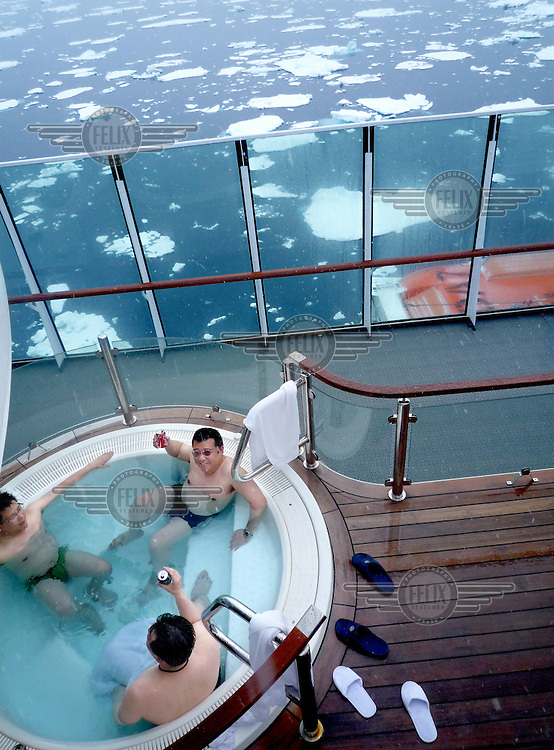 photograph by XAVIER CERVERA 06/2010.Three Chinese young men drinking beer and talking in the norwegian vessel MS Fram jacuzzi seventh floor meanwhile they can see melting ice in Greenland sea, next to Spitsbergen island, Svalbard archipielago