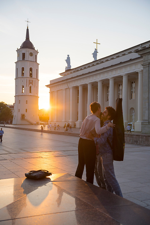 Vilnius, Lithuania - August 10, 2015: Friends greet one another with an embrace and kiss in Cathedral Square in Vilnius, Lithuania.