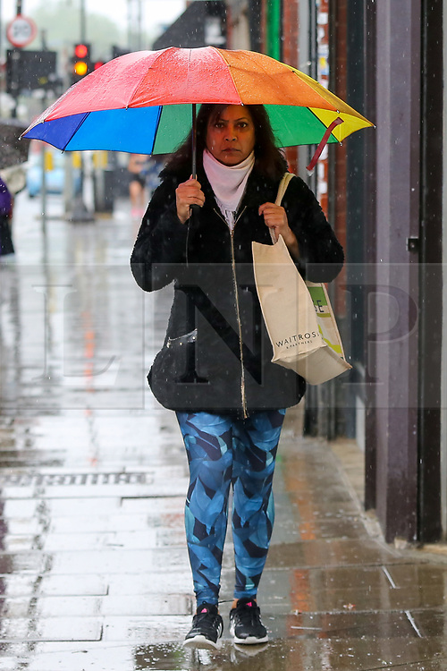 © Licensed to London News Pictures. 04/06/2021. London, UK. A woman shelters from the rain beneath a LGBTQ+ coloured umbrella during rainfall in north London. According to The Met Office, more rain is expected today across London and the South East of England, with the hot weather returning tomorrow. Photo credit: Dinendra Haria/LNP