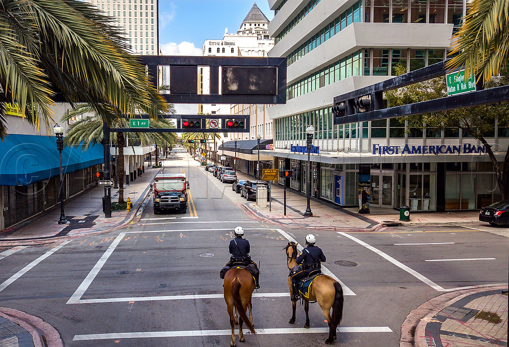 City of Miami Mounted Patrol Officers Loisel Cruz riding Ike, at left, and Ruben Gonzalez riding Cody, at right, patrol along a quite and mostly shuttered Flagler Street due to the threat of COVID19 pandemic in downtown Miami on Wednesday, April 1, 2020.