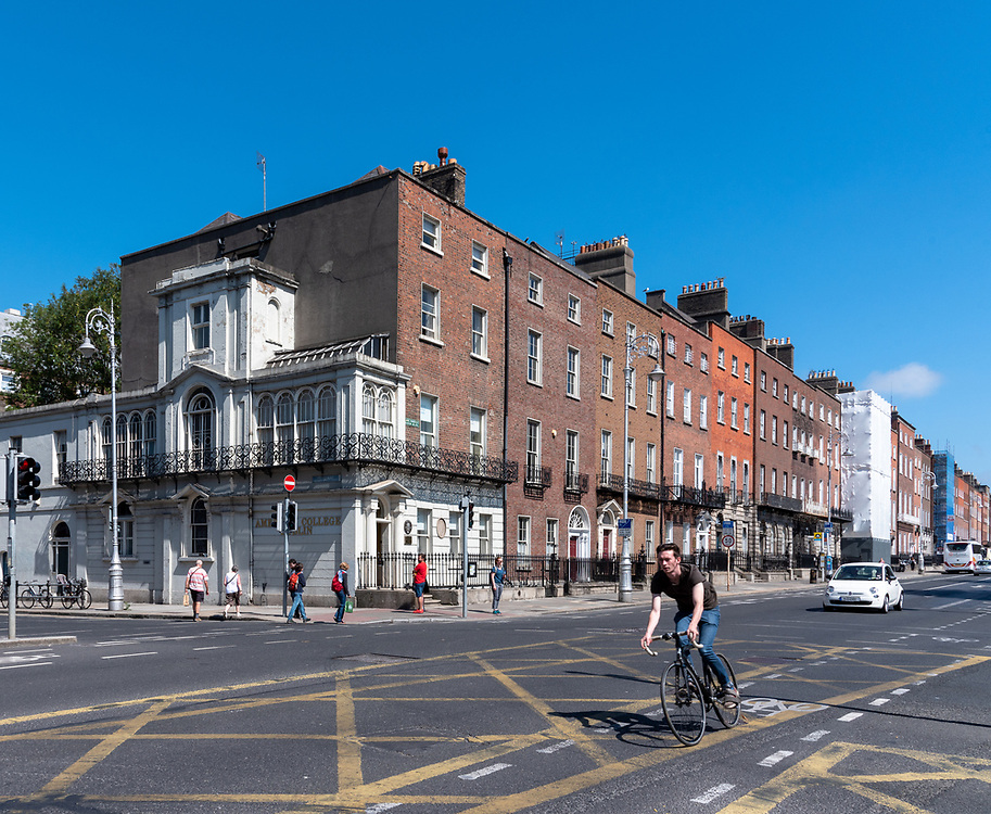A bicycle rider whizzes down the bike lane under a blue sky in Dublin, Ireland.