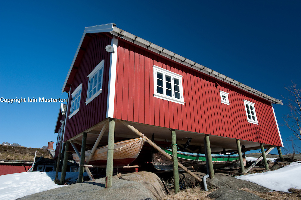 Traditional red wooden Rorbu fisherman`s hut with fishing boats stored below in village of Reine in Lofoten Islands in Norway