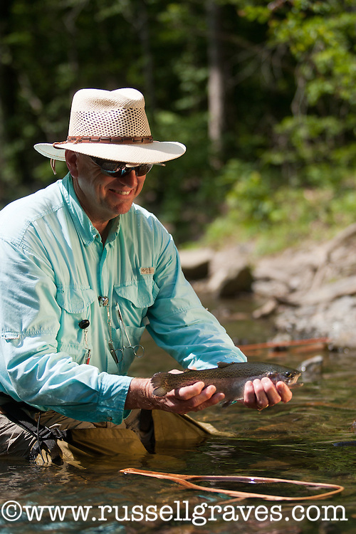 FLY ANGLER SHOWING OFF A RAINBOW TROUT CAUGHT FROM THE MOUNTAIN FORK RIVER IN BROKEN BOW, OKLAHOMA