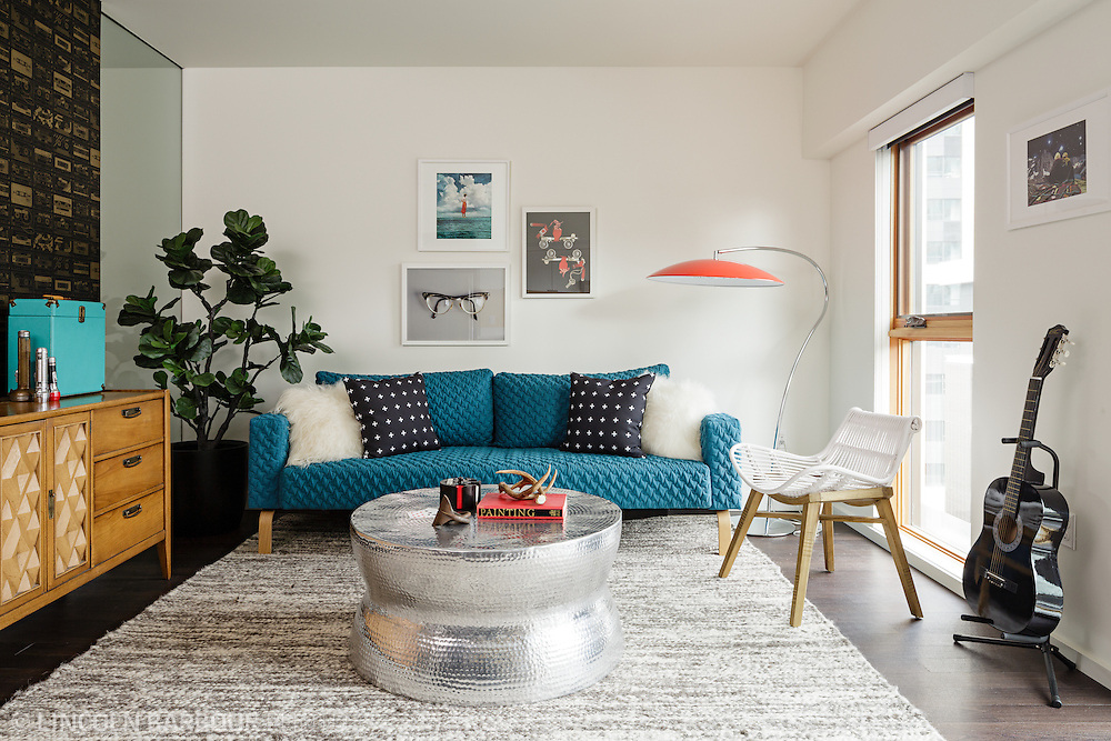 A well decorated apartment living room. Modern furniture and decor with bright pops of color.