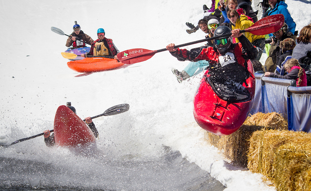 Josh Stupka and his kayak bounce off spectator barriers as he leads his heat, toward his eventual win over other competitors racing down a flume built of snow in the annual Kayaks on the Snow event at Monarch Mountain. Photo ©2014 Greg Smith