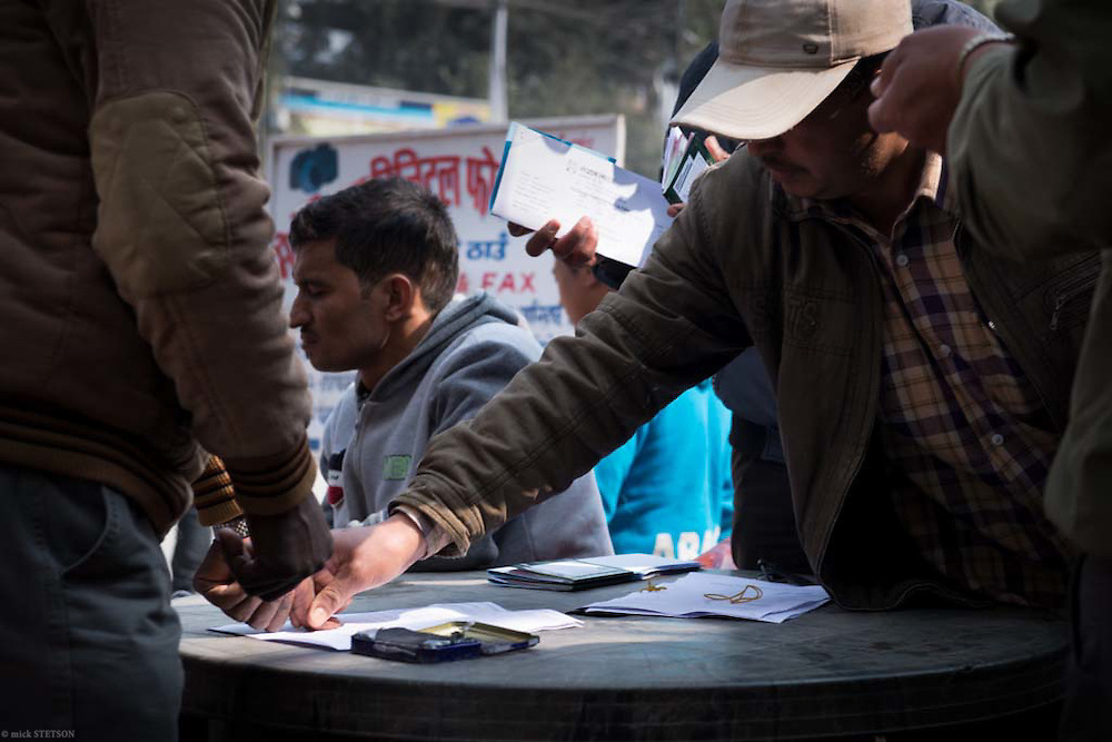 — Across from the main entrance to Kathmandu’s international airport, employment brokers assist Nepali men with completing the necessary paperwork they need in order to work overseas. Desperation and hope are the bedfellows that motivate these workers: desperation because there’s little work for them in modern Nepal; and hope that their sacrifice will help their family.