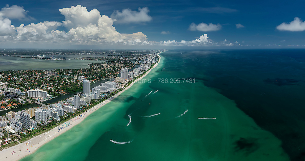 Aerial panorama of Miami Beach featuring Ocean drive, hotels and the shallow waters off the sun-dreched beach. Aerial of Miami Beach featuring Ocean Drive, hotels and the shallow waters off the sun-drenched beach, with dramatic clouds in the background.