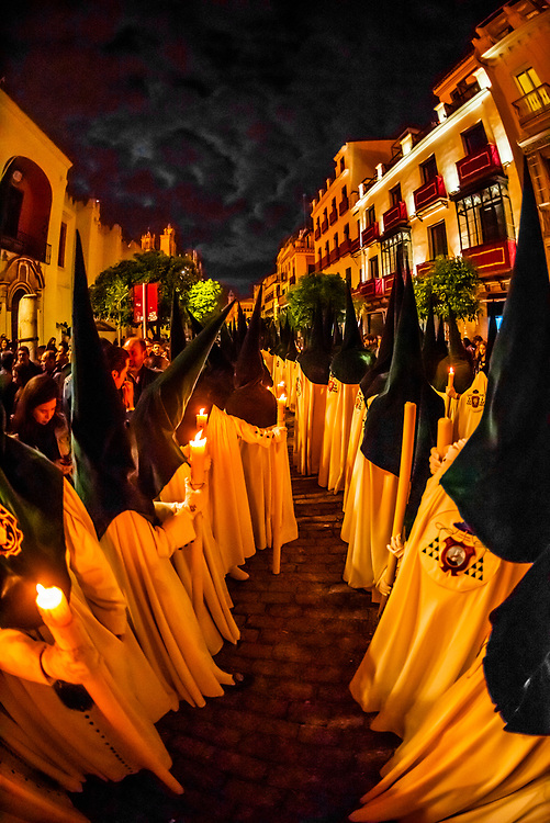 Hooded Penitents (Nazarenos) in the procession of the Brotherhood (Hermandad) La Macarena, early morning on Good Friday, Holy Week (Semana Santa), Seville, Andalusia, Spain.