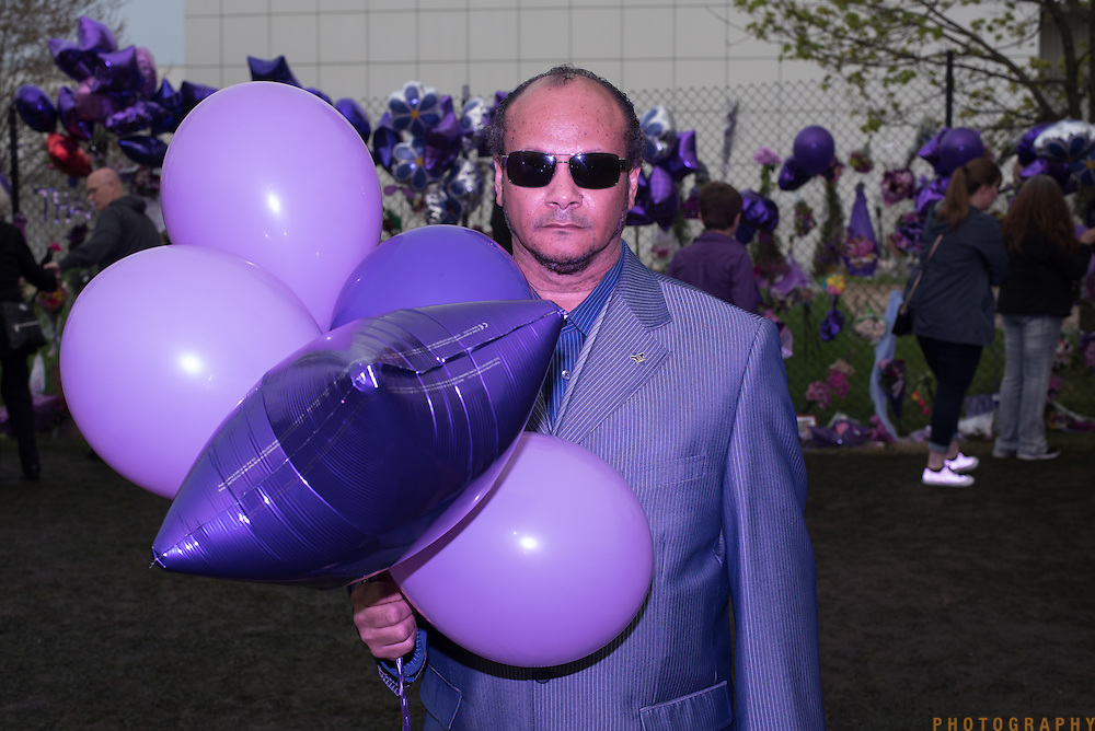 Purple people: Ervin Wright, of North Minneapolis, brings balloons to Prince's home and studio, Paisley Park, in Chanhassen, Minnesota, which became a memorial pilgrimage site after the announcement of the musician's death, in the late afternoon on Sunday, April 24, 2016. <br />
<br />
*purple people photographed with a purple gel on my flash. <br />
<br />
Photo by Angela Jimenez <br />
www.angelajimenezphotography.com