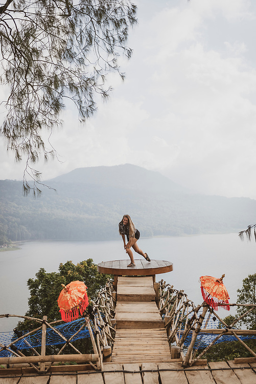 Bali, Indonesia - September 22, 2017: A young woman visiting Bali does a twirl while enjoying the beautiful view from a platform high above Lake Buyan.