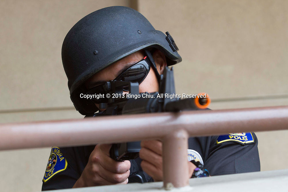 A police officer aims his machine gun during a joint training exercise simulating an ``emergency crisis'' at a school held by the Alhambra Police Department and the Alhambra Unified School District on Friday, June 14, 2013 in Alhambra, California. One week after a gunman killed 5 people at Santa Monica College, the city went ahead with a previously scheduled training exercise. (Photo by Ringo Chiu/PHOTOFORMULA.com)